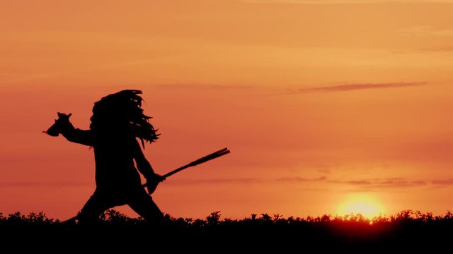 Silhouette of Native American hunts on background at sunset.