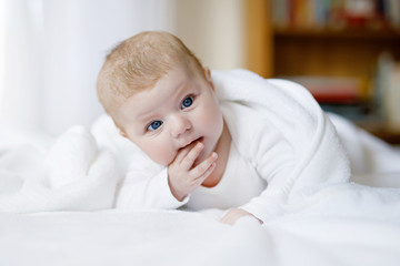 Baby girl wearing white towel or winter overal in white sunny bedroom