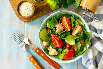 Concept for a tasty and healthy meal. Salmon Grilled Salad with cucumber, tomatoes, fresh arugula and sesame seeds. Home made food. Top view flat lay.