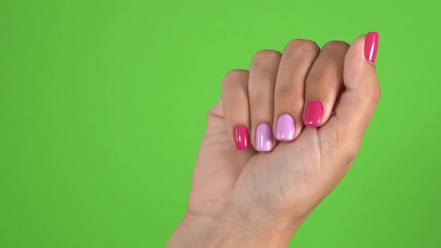 Closeup view of two hands of woman isolated on green screen background. Beautiful stylish trendy two colours manicure made with pink and purple gel polish. Real time 4k video footage.