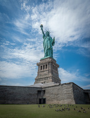 Fototapeta premium Shot of the Statue of Liberty in New York City, Usa. The shot is taken during a beautiful sunny day with a blue sky and white clouds in the background 