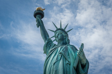 Fototapeta premium Shot of the Statue of Liberty in New York City, Usa. The shot is taken during a beautiful sunny day with a blue sky and white clouds in the background 