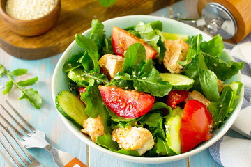 Concept for a tasty and healthy meal. Salmon Grilled Salad with cucumber, tomatoes, fresh arugula and sesame seeds. Home made food.