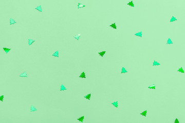 Green metallic foil christmas trees confetti sparse on trendy neo mint colored background. Simple...