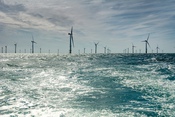 Wind farm seen across the sea on sunny day