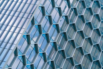 Office buildings. Structure of hexagon windows in futuristic technology network connection concept. Blue glass modern architecture facade design with reflection of sky in urban city, Downtown.