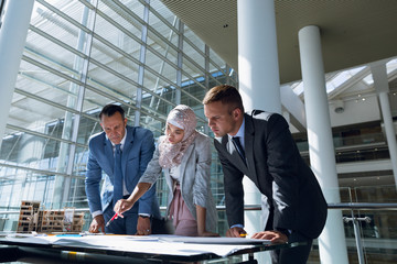 Male and female architects discussing over blueprint in office