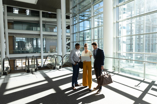 Young Business People Stand Using Laptop In Modern Office Lobby