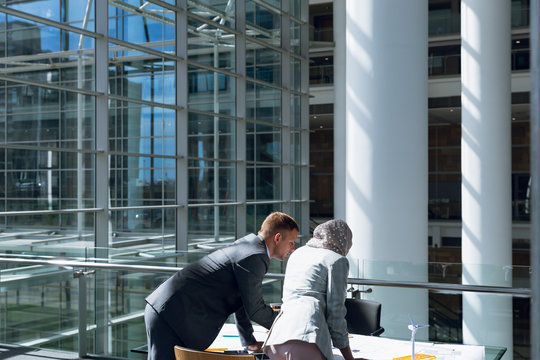 Male and female architects discussing over blueprint in office