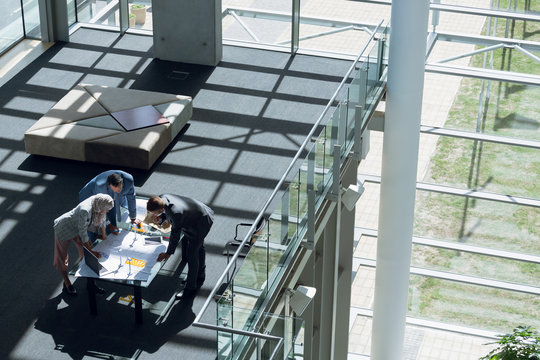 Male and female architects discussing over blueprint in office