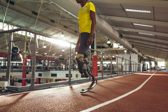 Low section of disabled athlete standing on running track in gym