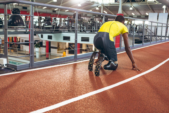Disabled African American male athletic in starting position on running track in fitness center