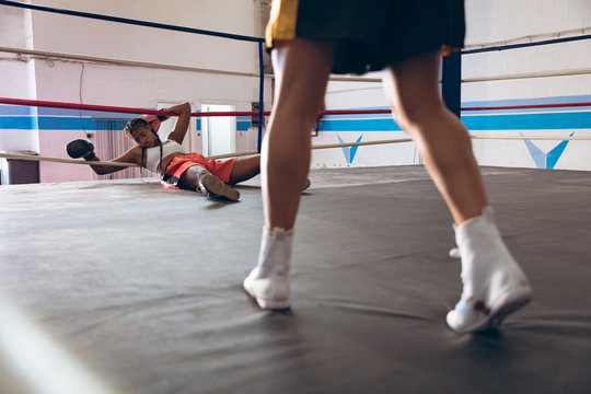 Female boxer lying in boxing ring at fitness center