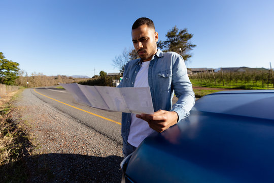 Youn man reading a map by a pick-up truck