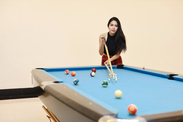 Fototapeta premium beautiful and sexy asian woman in black dress playing billiard or snooker on blue pool table with happy smiling face during holiday vacation