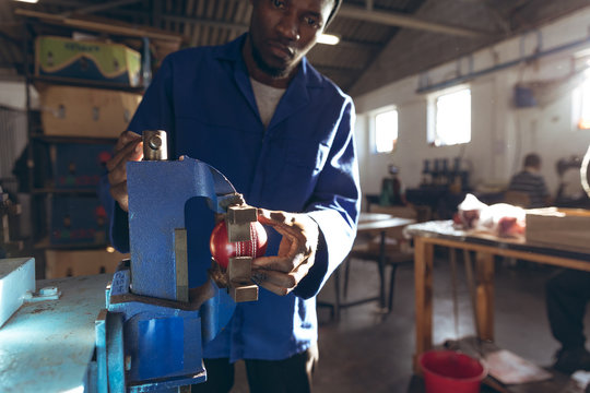 Man operating machine in cricket ball factory - Powered by Adobe