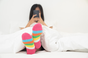Female foot in warm stripe wool sock ,Woman sleeping and relaxing in bed concept. Woman in bed...