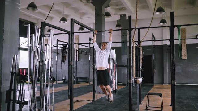 Inverse pull-ups to chest to be fit. Best exercises in the gym. Strong middle-aged man pulls up on bar in gym and wears lift and grip gear. Daily routine in crossfit gym and everyday exercise