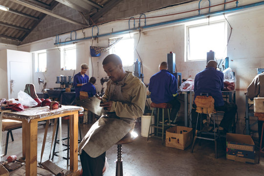 Young man holding a clipboard and writing in a cricket ball factory