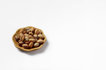wood plate of salted pistachio nuts isolated on white background.
