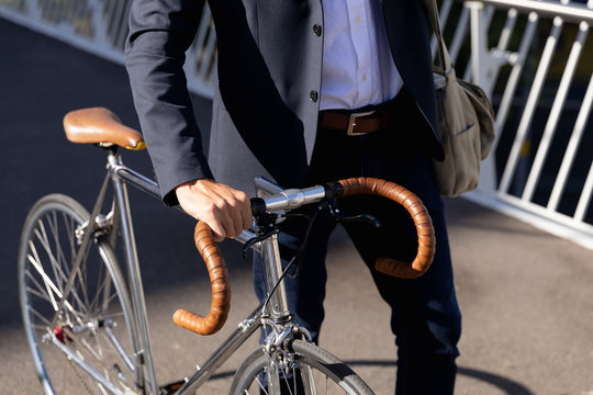 Young professional man walking with a bike