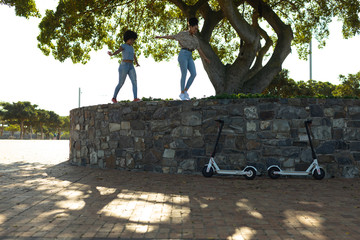Two young women walking on a wall