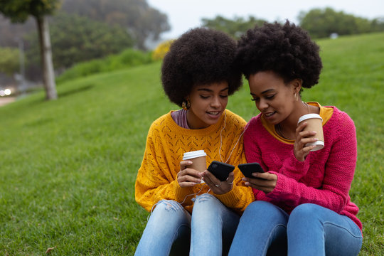 Two young women using smartphones outdoors