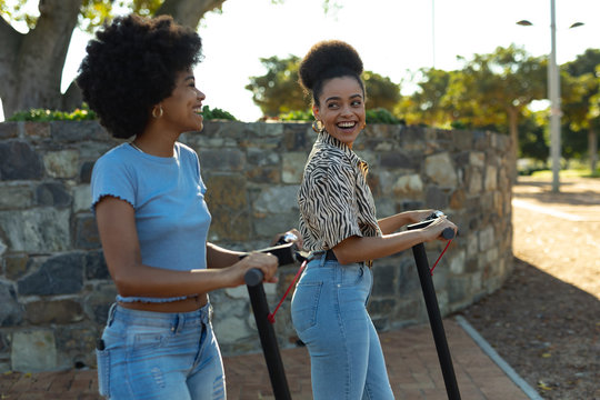 Two young women riding e scooters - Powered by Adobe