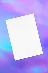 Empty white rectangle poster mockup lying diagonally with soft shadows on holographic background. Flat lay, top view