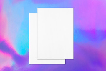 Two empty poster mockups lying on top of each other on holographic background