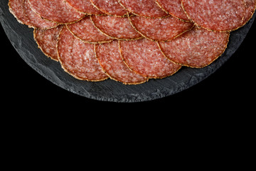 Plate with delicious sliced sausages on stone board. copy space. top view