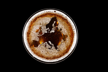 map of europe shape on foam in glass of beer on black background Top view