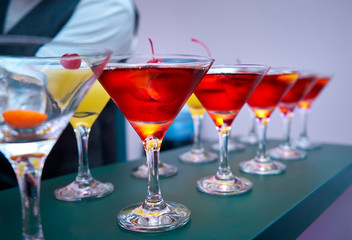 Beautiful glasses stand on the table. The bartender poured a cocktail there