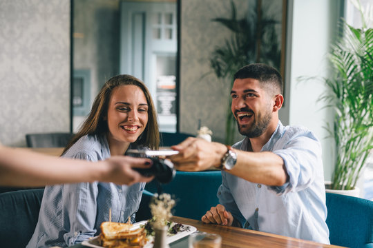 man paying bill contactless with smartphone in restaurant