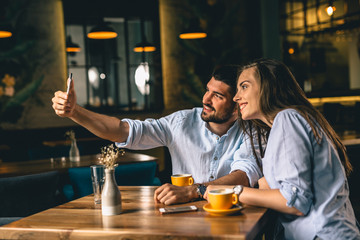 young couple taking picture with smartphone in restaurant