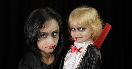Woman and child dracula. Halloween vampire make-up. Kid with blood on her face