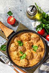 Meatballs in sour cream and tomato sauce in a frying pan on stone table. Top view flat lay. Free space for your text.