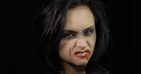 Fototapeta premium Vampire Halloween makeup. Woman portrait with blood on her face.