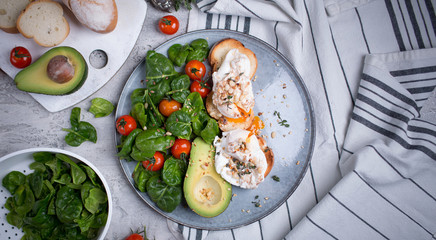 Toasts with avocado and poached egg, tomatoes and spinach, On a light gray background, Fresh morning breakfast
