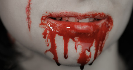 Bloody mouth and teeth of girl. Vampire Halloween makeup with dripping blood