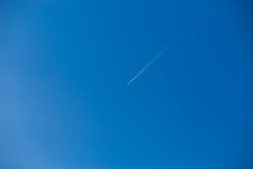 Diagonal airplane trace on free clear blue sky background