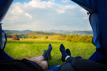 Two people lying in tent, view from inside. Couple camping with beautiful view of mountains