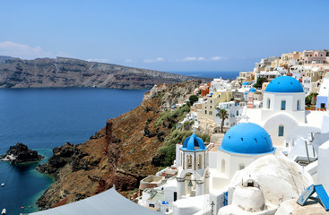 Fototapeta na wymiar The blue domes and white buildings of Santorini looking over the blue Aegean Sea, Greek Islands