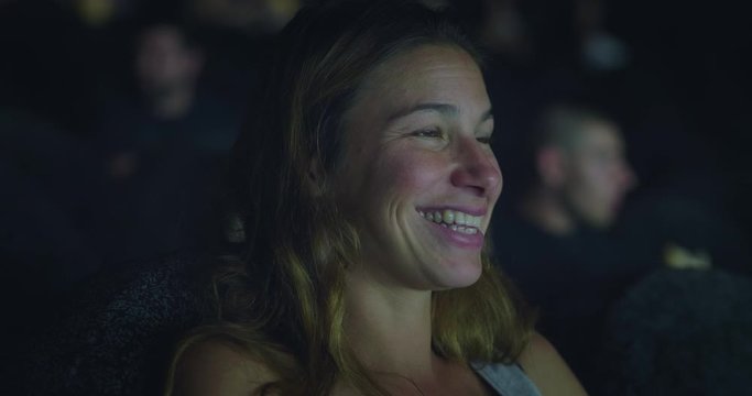 Authentic shot of an young woman is excited to enjoy a movie in cinema.