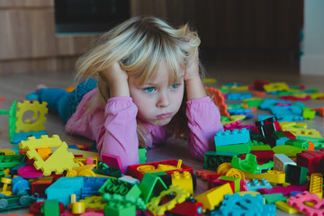 sad little girl, stress, exhaustion with toys scattered around