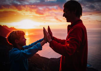 father and son high five at sunset mountains, family travel