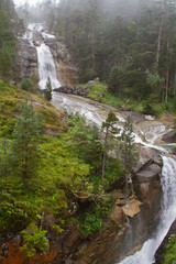 Wild river with waterfalls streaming through misty forest