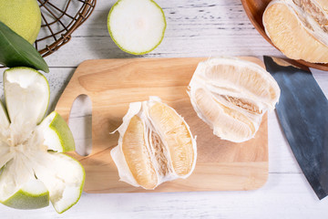Fresh peeled pomelo, grapefruit, shaddock with green leaf on bright wooden plank table. Seasonal fruit near mid-autumn festival, top view, copy space
