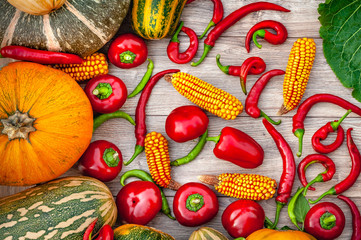 Autumn harvest vegetables. Pumpkin, corn, red and green peppers on a wood background.
