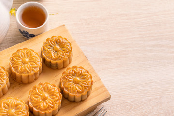 Moon cakes with tea on bright wooden table and serving try, holiday concept of Mid-Autumn festival traditional food layout design, close up, copy space.